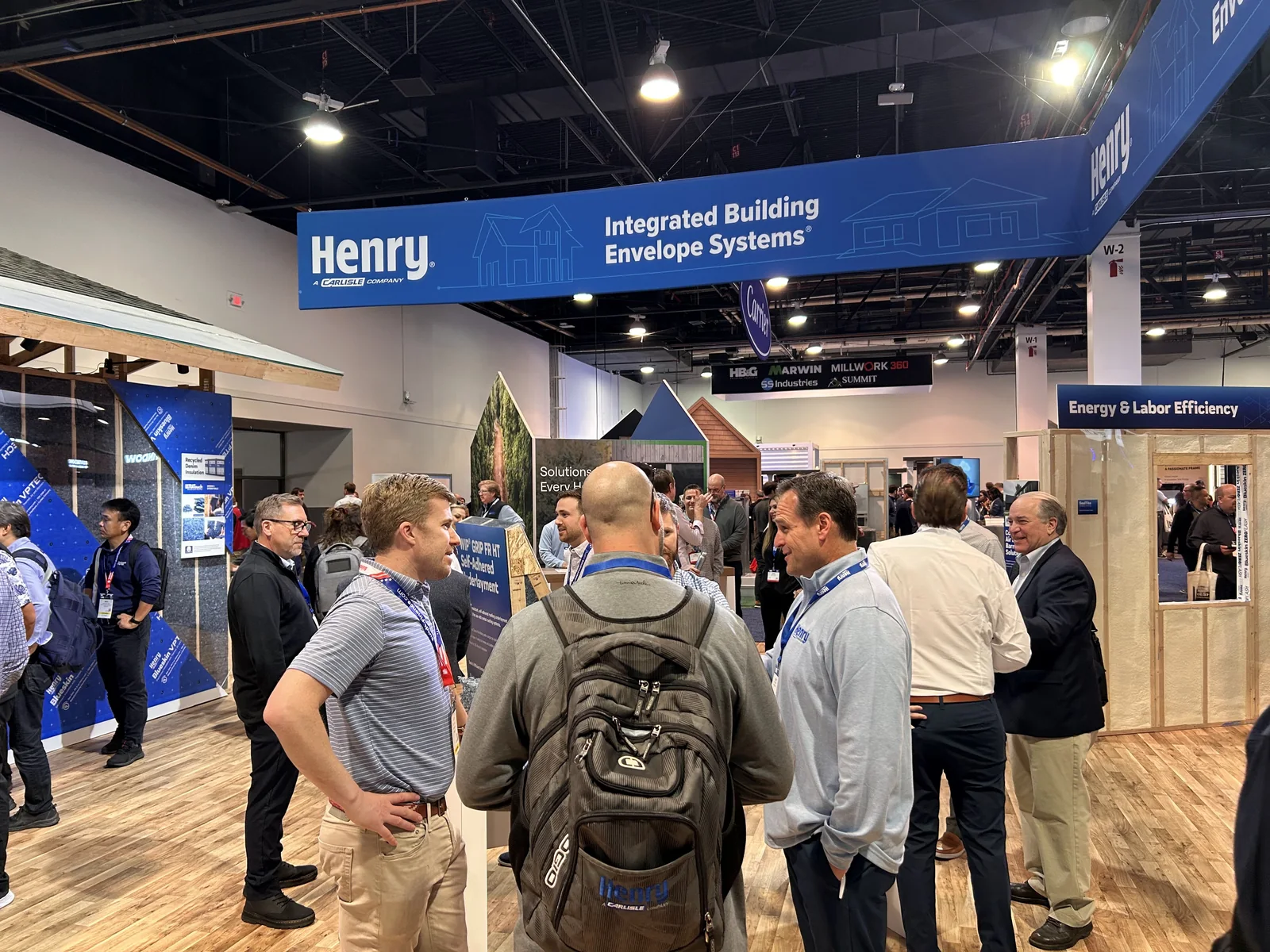 A full booth: builders talking under the Henry sign