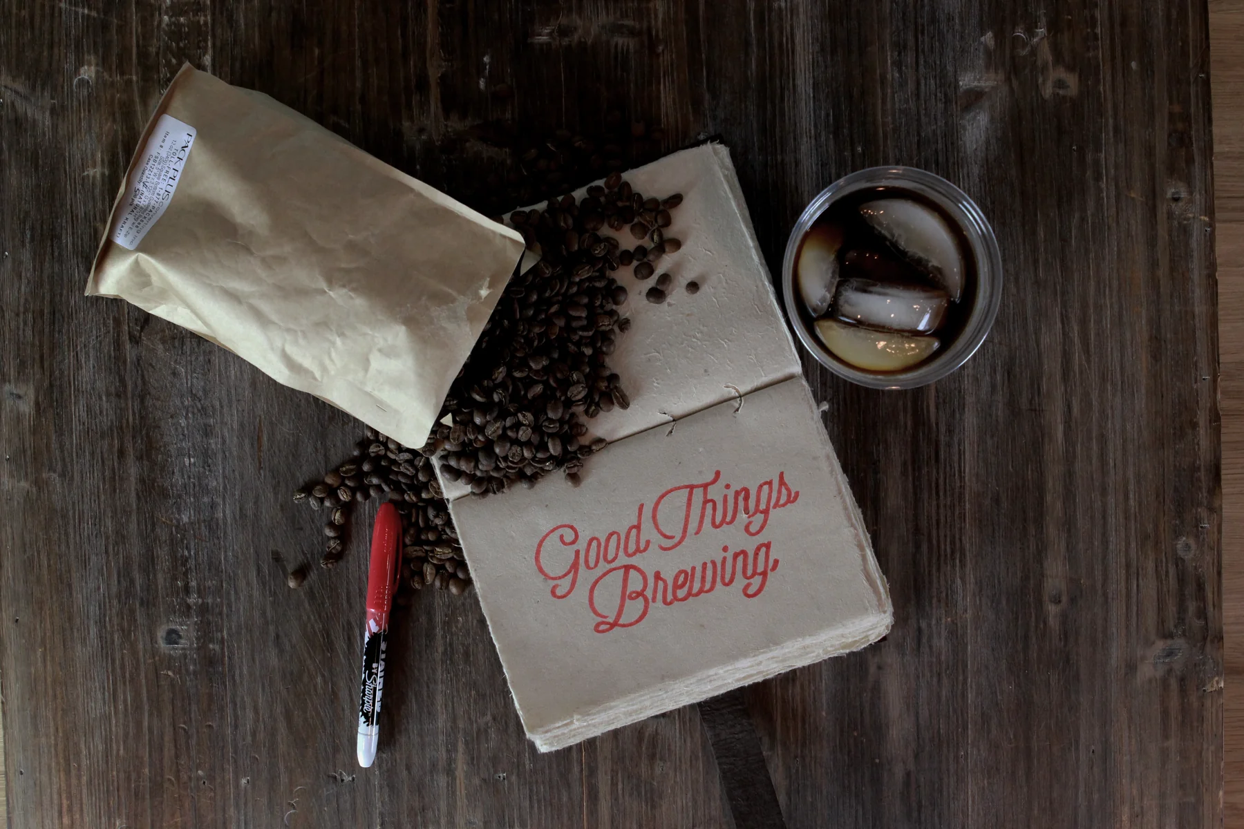 Good Things Brewing on a kraft bag, beans and cold brew on wood